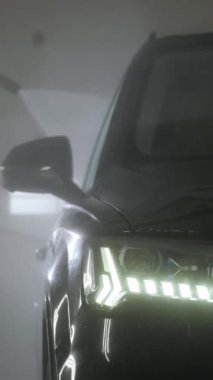 Dikey video. Bir oto yıkama işçisinin Bokeh eli bir oto yıkamada yüksek basınçlı çamaşır makinesiyle siyah bir arabanın sürücünün kapısını yıkar. Otomobilin tam önünde..