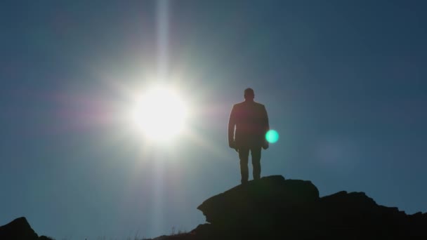 髪のない男のシルエット 完全な高さ 丘の上に立って太陽を見ています 輝く円盤は人から離れていく 映画ドローンによる撮影 — ストック動画