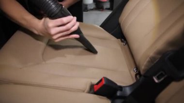 Bir işçi pahalı bir arabanın içindeki beyaz deri koltukları süpürür. Ayrıntılı hizmetler.