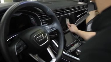 Lutsk, Volyn / Ukrayna - 10 Haziran 2023: Audi Q5 arabasının gösterge paneli. Kadın elleri merkez konsol ekranındaki toz ve kiri temizlemek için temizlik fırçası kullanır. Araba temizleme.