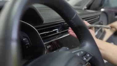 Kadınların elleri bir temizlik fırçası kullanır ve bir araba klimasının havalandırma ızgarasından tozu çıkarır. Araba temizliği mi yoksa vale konsepti mi?.