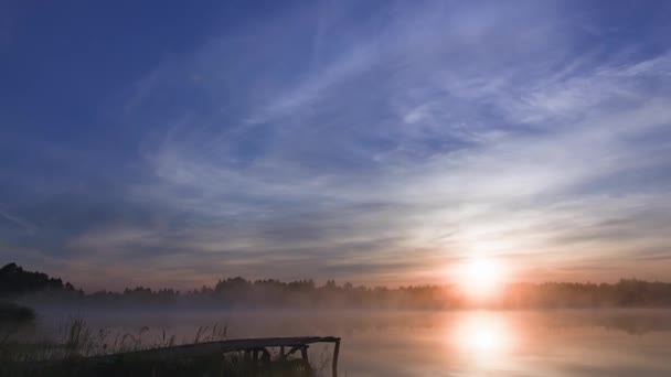夏日的雾蒙蒙的早晨 日出笼罩湖面 还有木桥和森林 水面上的天空反射出的光芒 自然与环境 — 图库视频影像