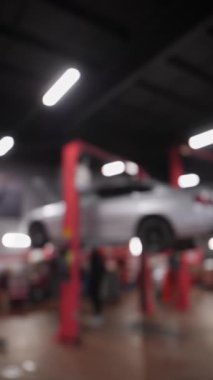 Dikey video. Tamirci Araba Tamir Merkezi 'nin bulanık arka planı ve Servis İstasyonundaki Arabalar için Elektrik Kırmızı Asansör. Gri arabalı elektrikli asansör. Odaklanmamış video.