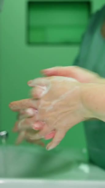 垂直录像 两名医生在诊所关闭标准洗手程序 手指和手掌上有泡沫 水龙头里流出的水 外科准备工作 — 图库视频影像
