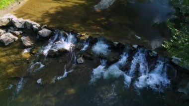 Hava görüntüsü. Kayalık akıntıların üzerinden akan temiz suyla bir dağ nehrinin üzerinde yükseliyor. Hornbeam ağaç dalı. Yaz mevsimi.