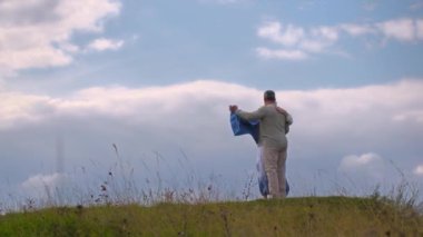 Yaşlı çift tepelerde bulutlu bir gökyüzüne karşı vals yapıyor. Mutlu aile hayatı kavramı.