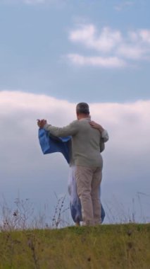Dikey video. Yaşlı çift bulutlu bir gökyüzüne karşı vals yapıyor..