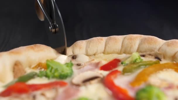 ラウンドピザナイフは 新鮮なピザの表面に転がり それを切ります 車輪の表示パプリカ ブロッコリー チーズ クローズアップ — ストック動画