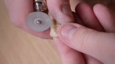 Dikey video. Kapatın. Diş teknisyeninin elinde dişleriyle yapay çene kalıbı var. Diş laboratuarında seramik kaplamalarla çalışıyor. Dişçi el değirmeni.