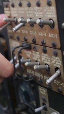 Dikey video. Pilotlar eski bir uçağın kokpit gösterge panelinin düğmelerini değiştiriyorlar. Uçak yapım tarihi konsepti.
