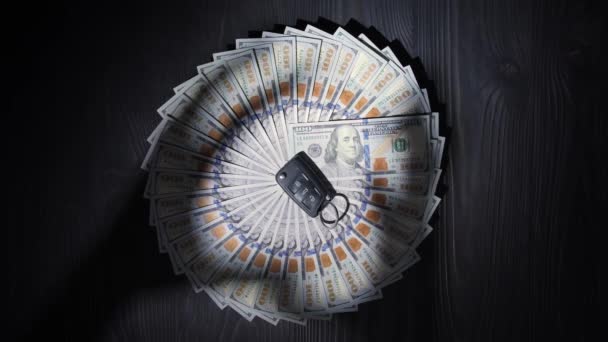 一百美元的钞票在木制桌子表面上呈圆形 在钱的中间是汽车上的一个关键的雾气 手的影子试图拿走所有的现金和钥匙 — 图库视频影像