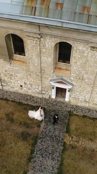 Вертикальное Видео Молодая Невеста Свадебном Платье Подходит Жениху Обнимает Фоне — стоковое видео