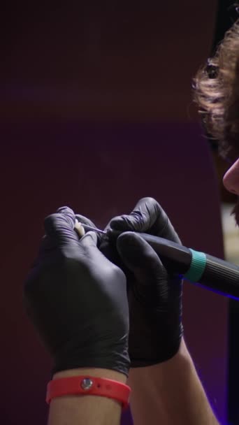 バーティカルビデオ 若いブルネットの男は歯科実験室で磨く陶磁器の冠が付いている人工顎と働きます — ストック動画