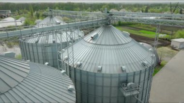 Hava görüntüsü. Kırsal alanda metal geçitlerle çevrili üç büyük tahıl ambarı. Bükülmüş metal silindirler tahıl depolamak için kullanılıyor. Endüstriyel tarım altyapısı.