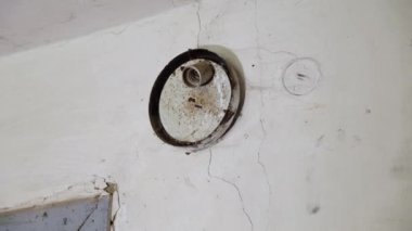 Örümcek ağları, çatlaklar ve metal bir armatürle yaşlanmış tavan. Alet beyaz bir porselen sokete sahip ve toz ve pas ile kaplı. Tavanda pislik var..