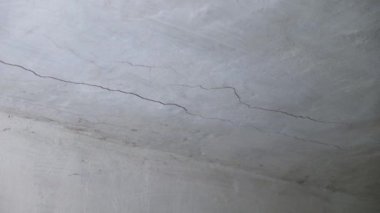 Kapatın. Çatlak ve örümcek ağlarıyla terk edilmiş eski beyaz çimento tavanı. Her yerde toz ve toprak var. Yaşı ya da yapısal gerilimi gösteriyor..