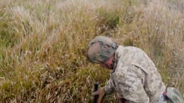 Yaralı, sol eli kanlı bir Ukraynalı asker birkaç adım atıp çimlere düştü. Cesedin sol tarafında kurşun yarası var. Ukrayna 'da Savaş.