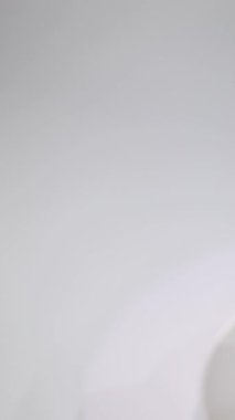 Dikey video. Beyaz bir tabakta Panettone Paskalya pastası ve badem parçalarıyla kaplı monoton bir arka plan.