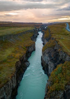 İki dağ arasında İzlanda 'da bir kanyon oluşturan nehrin güzel günbatımı