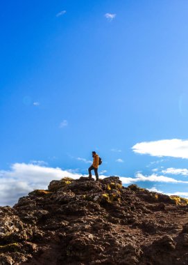 Güneşli bir günde İzlanda 'da dağın tepesinde bir adamın resmi.