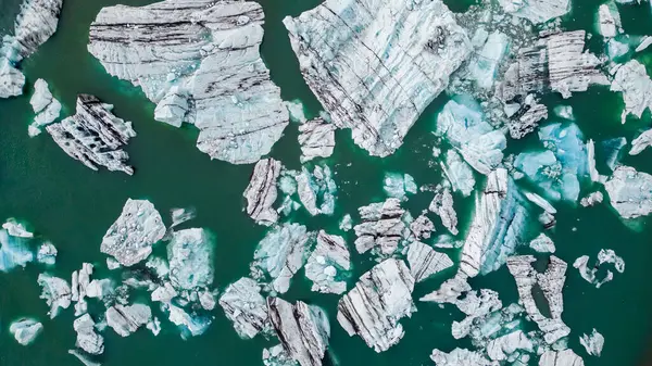 İzlanda 'daki yeşil bir göldeki buzdağından kopan buz parçaları.