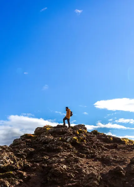 Güneşli bir günde İzlanda 'da dağın tepesinde bir adamın resmi.