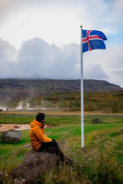 Dağdaki adam İzlanda bayrağına bakıyor.