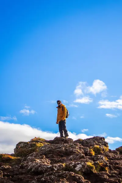Güneşli bir günde İzlanda 'da dağın tepesinde bir adamın resmi.