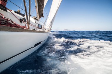 Yacht sailing fast on sea with waves towards Aeolian islands in Italy