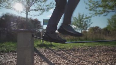 Acemi, Almanya 'da sokak sporları alanında spor ayakkabıları içinde ip üzerinde yürümeyi ve dengeyi öğreniyor. Erkek, Almanya 'da şehir idmanında lastik çizgilerde dengesini korumayı öğrenir