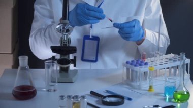 Laboratuvarda kan örneğiyle çalışan bir bilim adamı. Laboratuar analisti kan kaymasını analiz ediyor. Doktor ya da patolog cam levhaya insan kanı döker. Virüsü tanımlamak için biyolojik materyal.. 