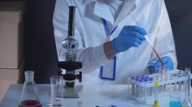 Laboratuvarda kan örnekleriyle çalışan bir patolog. Bilimadamı DNA örneğini laboratuvarda inceliyor. Sağlık sigortası, kan testi, kan araştırması. Laboratuvar çalışanı kan örnekleriyle slayt hazırlıyor.. 