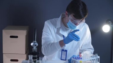 Laboratuvarda kan örneğiyle çalışan bir bilim adamı. Laboratuar analisti kan kaymasını analiz ediyor. Doktor ya da patolog cam levhaya insan kanı döker. Virüsü tanımlamak için biyolojik materyal.. 