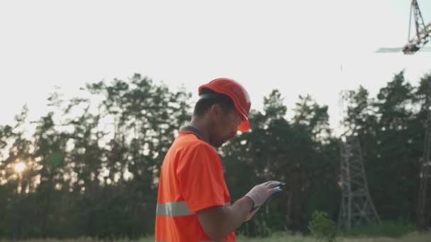 Человек Каске Оранжевой Рабочей Одежде Работает Планшет Электростанции Поле Возле — стоковое видео