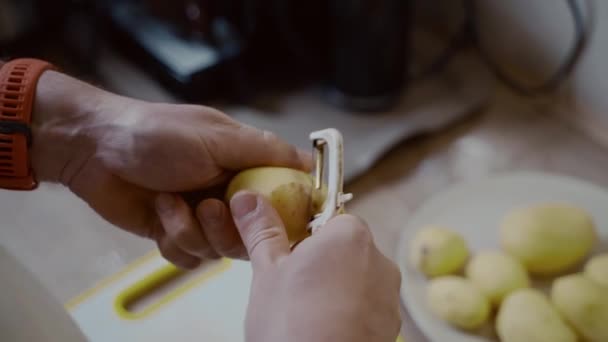 Caucasiano Macho Descascando Batatas Sobre Mesa Cozinha Doméstica Limpar Batata — Vídeo de Stock