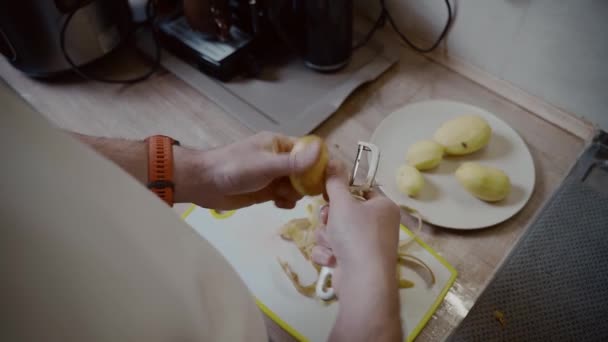 Mãos Perto Homem Descasca Batatas Com Faca Cozinha Casa Cozinhar — Vídeo de Stock