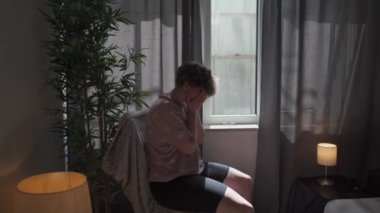 Evsel inzivaya çekilme. Depresyonda ve ahlaken yanmış bir kadın kafasını ve yüzünü evin penceresinden tutuyor. Kişinin profesyonel psikolojik yardıma ihtiyacı var. Depresyonda, stres altında ve yalnız hissediyorum.. 