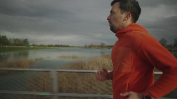 Uomo Jogger Felpa Arancione Corre Attraverso Ponte Legno Natura Scandinavia — Video Stock