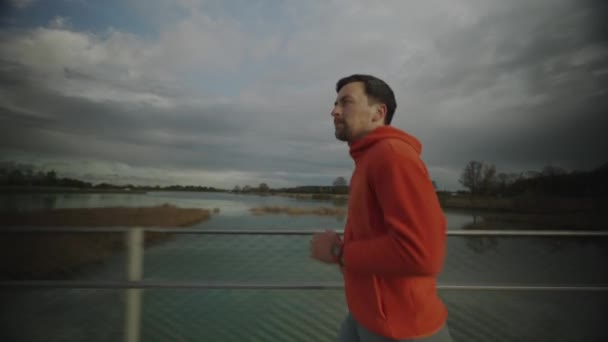 Άνθρωπος Δρομέας Πορτοκαλί Φούτερ Τρέχει Ξύλινη Γέφυρα Στη Φύση Στη — Αρχείο Βίντεο