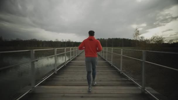 Mężczyzna Pomarańczowej Bluzie Biegnący Przez Park Narodowy Przez Drewniany Most — Wideo stockowe
