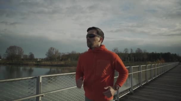Ein Mann Joggt Orangefarbenen Sweatshirt Herbst Über Eine Holzbrücke Der — Stockvideo