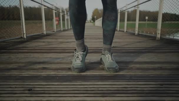 在寒冷的秋天里 穿着橙色和温暖衣服的人在木桥上慢跑前热身 跑步者伸展肌肉 腿和脚 准备跑到户外 跨国跑步 — 图库视频影像