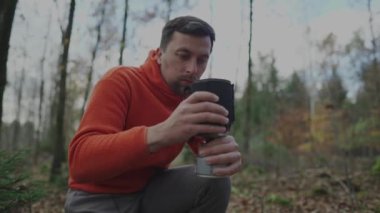 Yürüyüşçü ormanda kamp yaparken yemek pişirmek için bir sistem kurar. Gezgin ocakta yemek pişirmeye hazırlanıyor. Yürürken yemek ve içmek. Küçük ve taşınabilir pişirme sistemleri. Seyahat malzemeleri. Gaz sobası. 