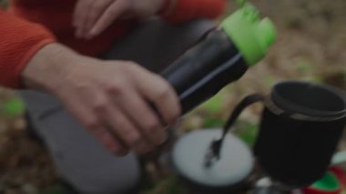 Yürüyüş yapan adam çay ve süblimleşen seyahat yemekleri yapmak için gaz ocağına su döker. Ormandaki kamp ateşi üzerinde kaynayan su. Kamp sobası sistemi.. 