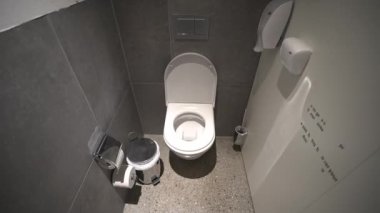 Kabinin içindeki modern umumi tuvalet, temiz bir tuvalet kağıdı, duvara monte edilmiş tuvalet kağıdı, çöp öğütücü ve dezenfektan. Banyonun içinde beyaz seramik klozet var. Hijyen kavramı. 