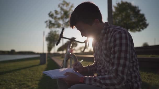 Étudiant Universitaire Prenant Des Notes Pour Les Devoirs Dans Parc — Video