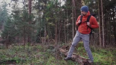 Dışarıdaki maceraperest adam ormanda sırt çantasıyla geziyor, vahşi doğada. Sonbahar orman yollarında sırt çantasıyla tek başına. Seyahat konsepti. Sonbahar ormanlarında yürüyen bir gezgin. İskandinav doğasının tadını çıkarmak