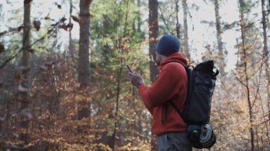 Yürüyüş yaparken açık hava haritaları. Yürüyüşçü, uygulama haritalama yoluyla ormanda yön bulmak için akıllı telefon kullanır. Akıllı telefondan güzergahlar çiziyor. Gezgin GPS kullanarak ormanda yolunu bulur. Keşfedin ve yürüyün. 