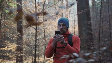Yürüyüşçü, sonbahar doğa yürüyüşü sırasında ormanda gezinmek için akıllı telefon kullanır. Gezgin ormanda yürürken telefonda GPS navigasyon uygulaması kullanıyor. Coğrafi Konum Sistemi. 