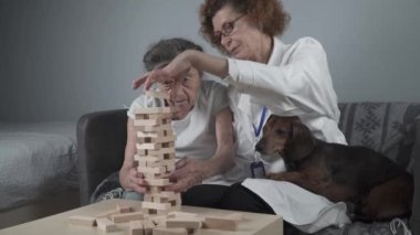 Hayvan terapisi, bunama ve Alzheimer hastalığından muzdarip yaşlıların bakımı. Kıdemli kadın ve doktor motor becerileri ve beyin egzersizleri yapıyorlar. Emeklilik merkezinde tahta blok kullanıyorlar.. 